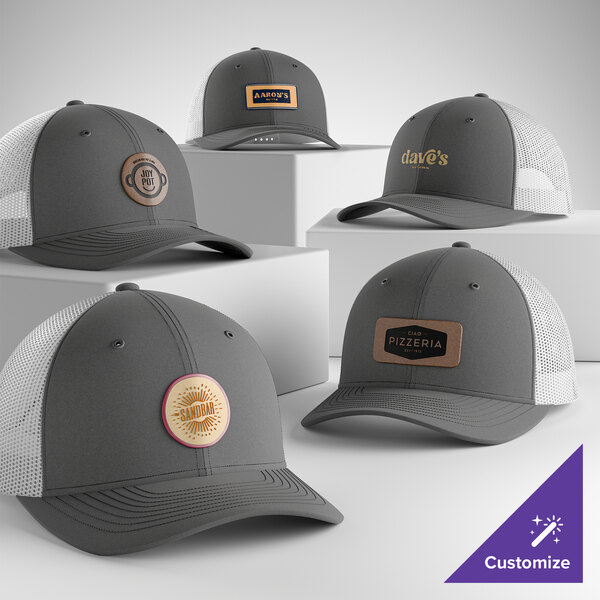 A collection of customizable graphite and white 6-panel trucker caps with mesh backs, featuring various business logos on the front.