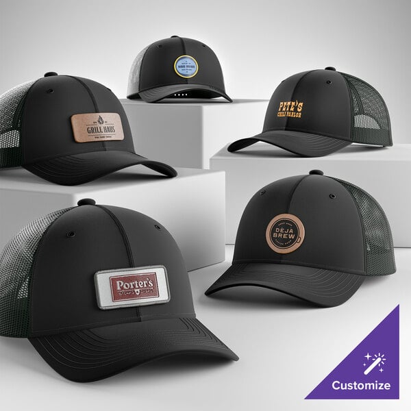 A collection of customizable black and grey 6-panel trucker caps with mesh backs and various logo patches displayed on white platforms.