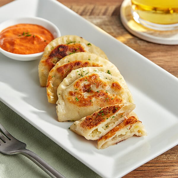 A plate of Jaju Jalapeno Cheddar Pierogies with a fork on the table.