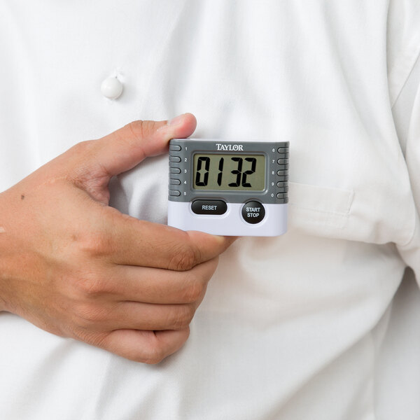 A person holding a Taylor 10-key digital kitchen timer.