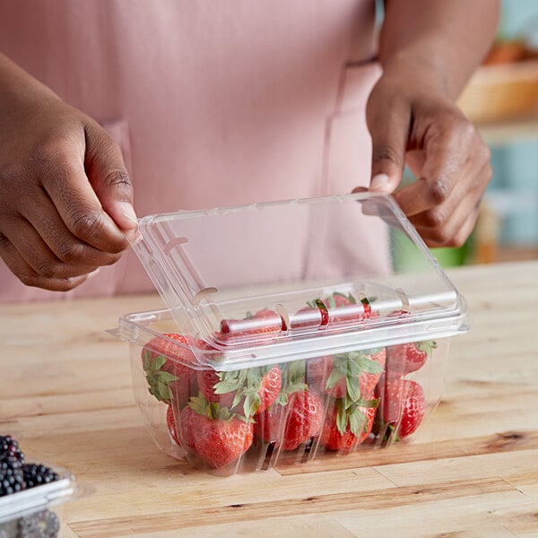 A woman holding a D&W Fine Pack plastic container of strawberries.