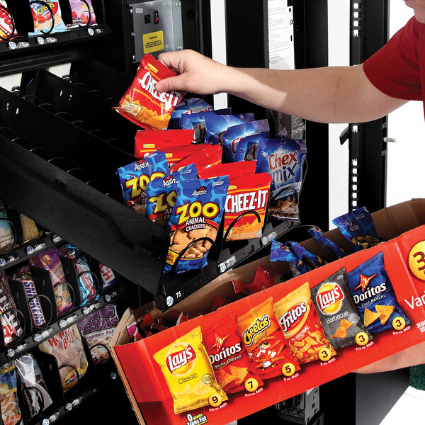 A man putting a bag of chips into a Selectivend snack vending machine.