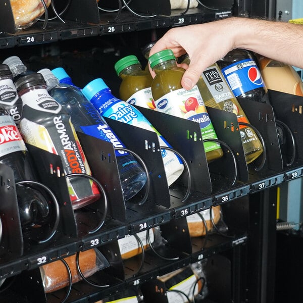 A hand reaching for a soda in a vending machine.