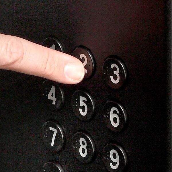 A finger pressing a number on a black keypad button.