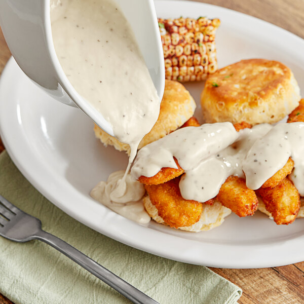 A plate of chicken and biscuits with Stouffer's white gravy being poured over it.