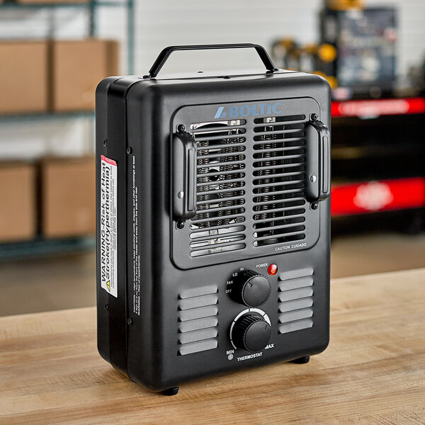 A black Boltic Portable Electric Milkhouse Heater on a wooden table with knobs and a red button.