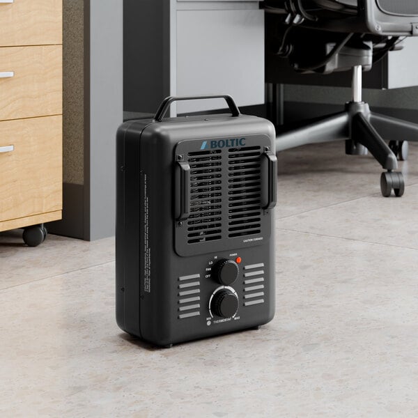 A black Boltic portable electric milkhouse heater with a handle and control knobs, placed on an office floor.