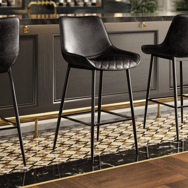 Three Lancaster Table & Seating black bar stools with black tufted vinyl seats at a bar.