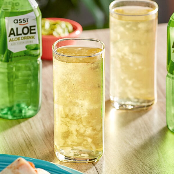 A table with a bottle and glasses of Assi Aloe Juice.
