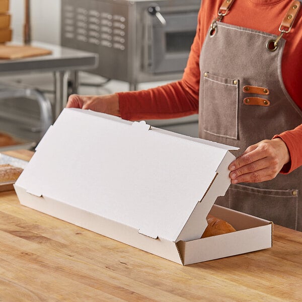 A woman in an apron opening a white Choice flatbread box.