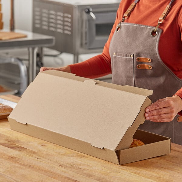A person wearing a brown apron opening a Choice cardboard box.