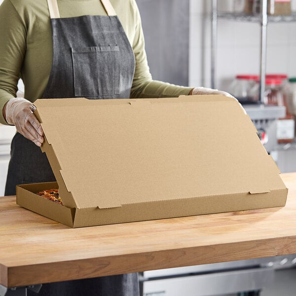 A woman in an apron holding a Choice kraft flatbread box.