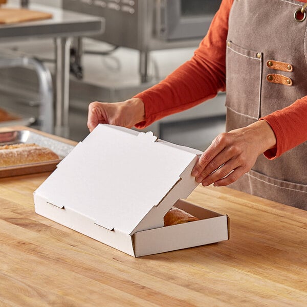 A person opening a Choice white corrugated flatbread box with food inside.