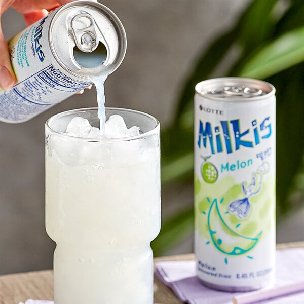 A hand pouring Milkis melon milk soda into a glass.