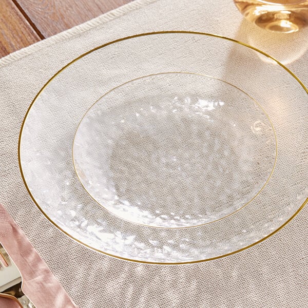 A clear plastic Visions coupe plate with a gold rim on a white tablecloth.
