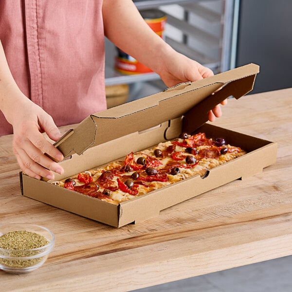 A person opening a Choice Kraft flatbread box to reveal a pizza.