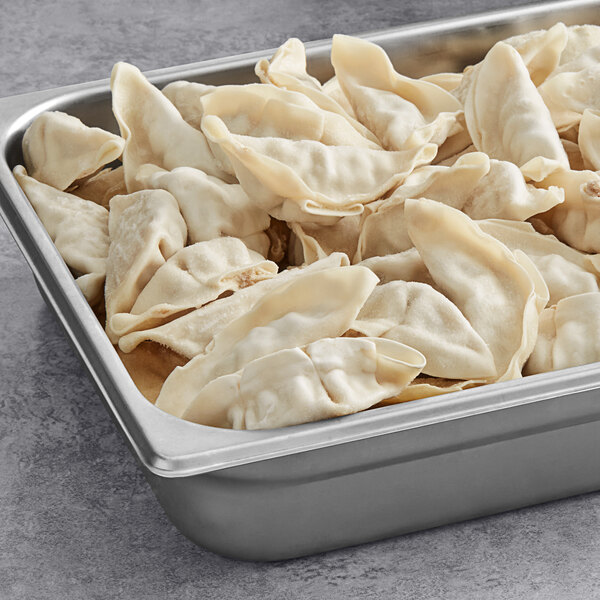 A silver pan filled with Chef One Pork and Napa Cabbage Dumplings on a table.