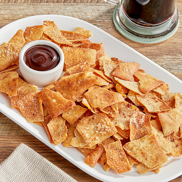 A plate of Issa's Cinnamon Sugar Pita Chips with a bowl of chocolate sauce on a table.