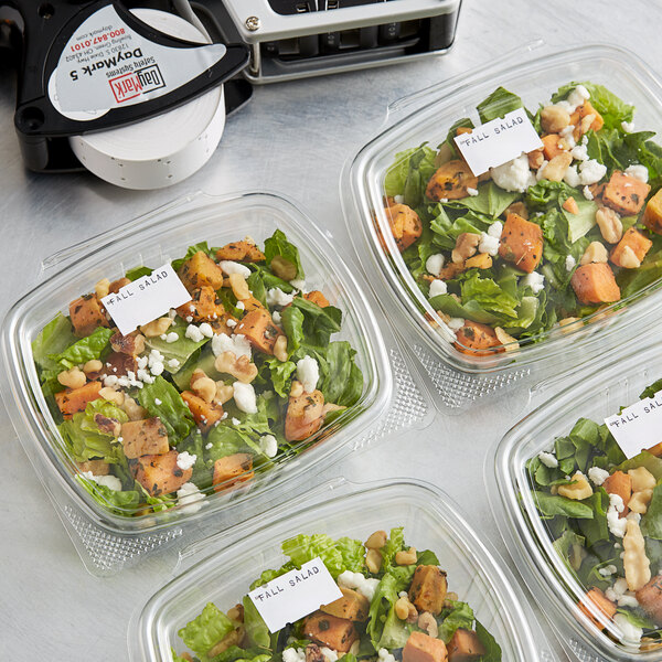 A salad in plastic containers with DayMark labels on a counter.