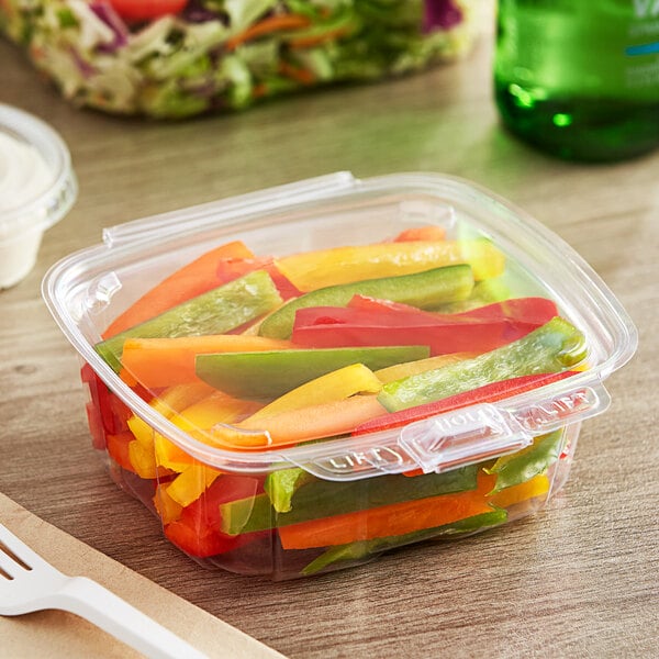 A Good Natured clear plastic clamshell package filled with vegetables on a counter with a spoon.