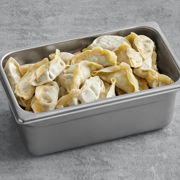 A silver metal container filled with Chef One kale, mixed vegetable, and tofu dumplings.