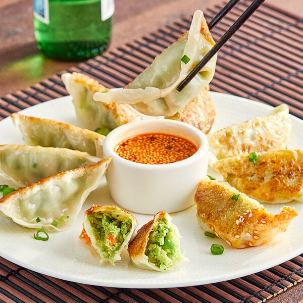 A plate of Chef One Edamame Dumplings with a bowl of sauce.