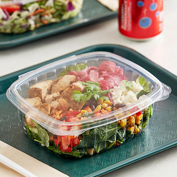A salad in a Good Natured clear plastic container on a table.