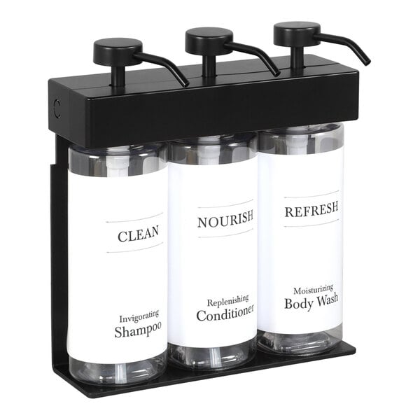 A black wall-mounted dispenser with three white oval bottles inside.