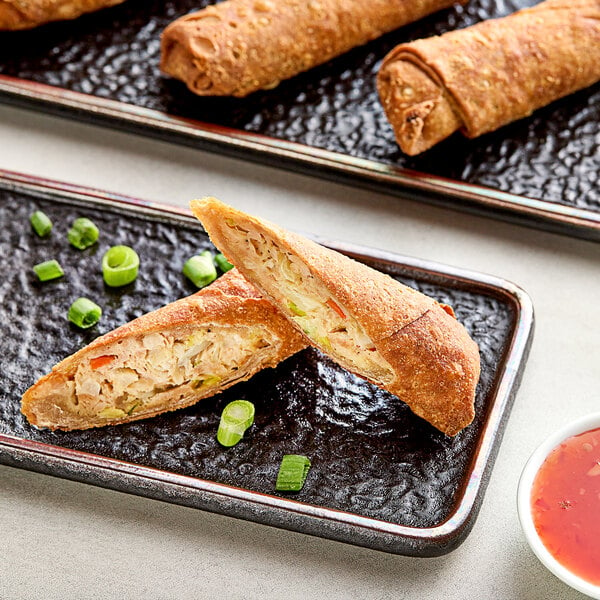 A white plate with a whole grain Minh chicken egg roll and dipping sauce.