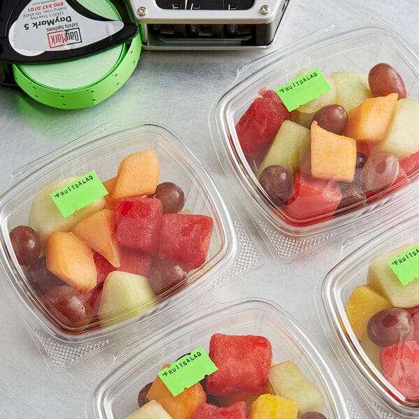 A group of plastic containers of fruit salad with DayMark fluorescent green date coder labels.