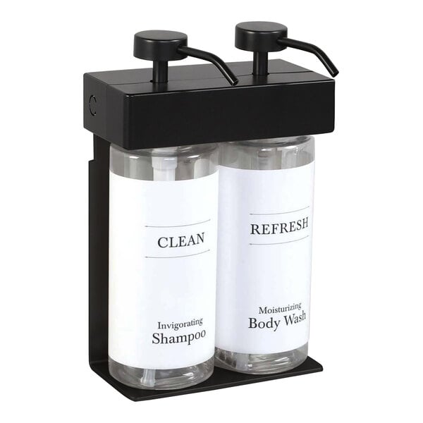 A white wall-mounted dispenser with black text and two black oval bottles inside.