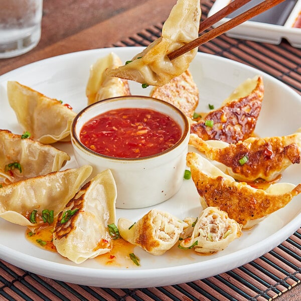 A plate of fried Chef One Pork and Vegetable Dumplings with dipping sauce.