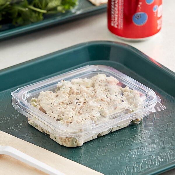 A clear Good Natured tamper-evident plastic container with food inside on a white tray.