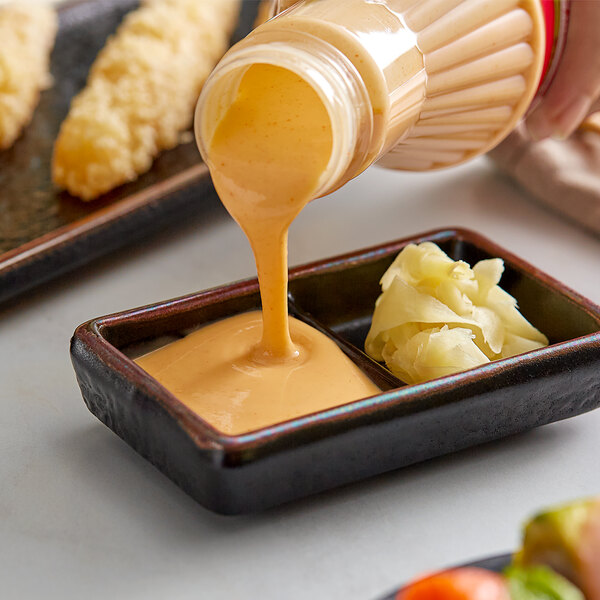 A bowl of food with Terry Ho's Yum Yum Sauce being poured into it.