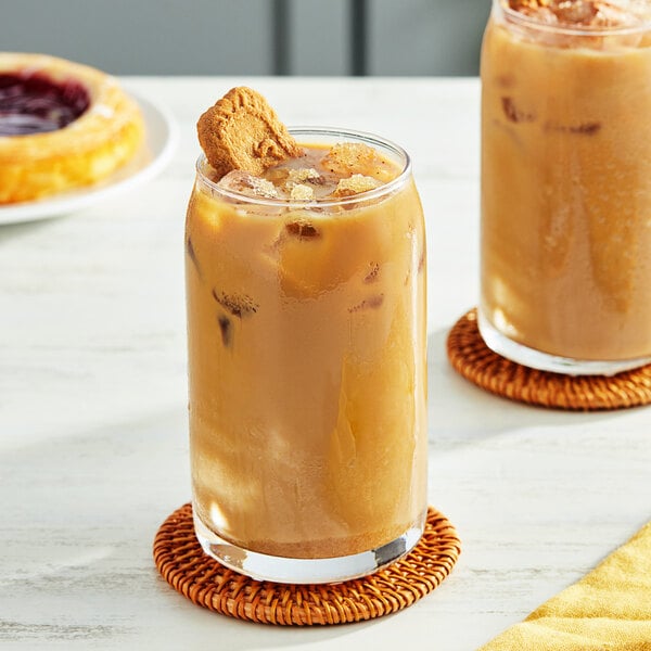 Two glasses of iced coffee with cookies on top on a table.