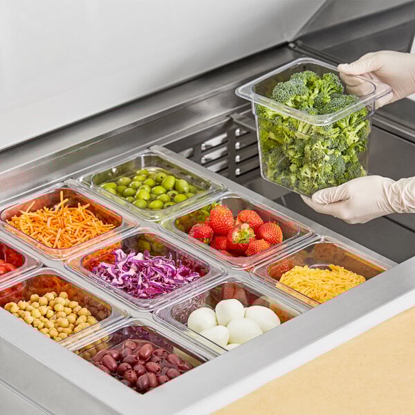 A person holding a clear plastic container of broccoli.