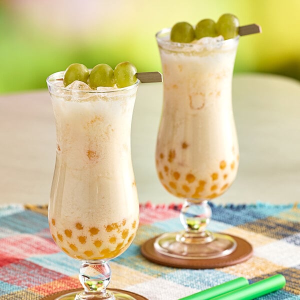 Two glasses of Fanale white grape drink with grapes in it.