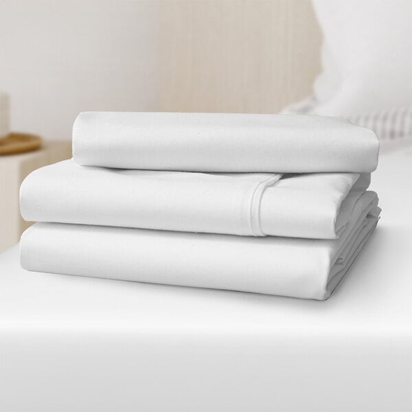 A close-up of a stack of white Oxford Micro Superblend fitted sheets.