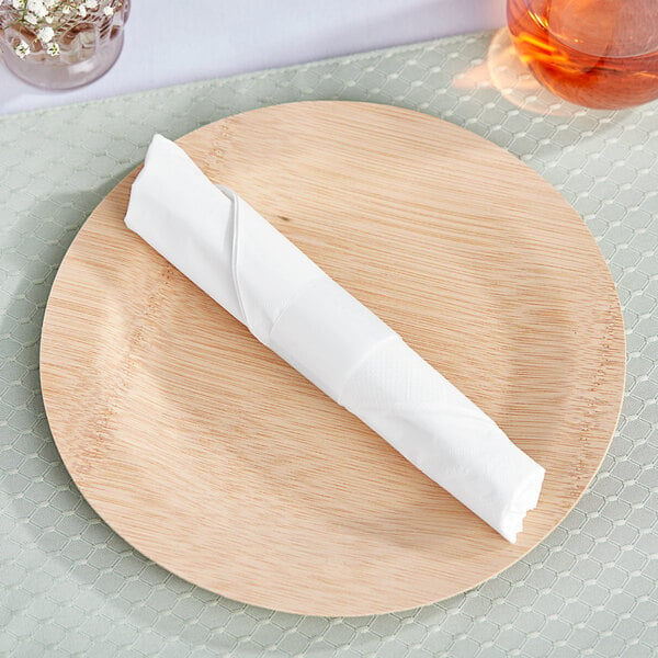 A wooden plate with a white Choice 1/4 Fold Dinner Napkin with a white napkin band rolled up on it.