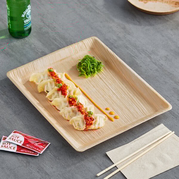 A rectangular Eco-gecko palm leaf tray with food on a wooden surface.