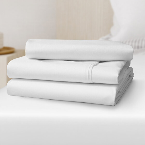 A stack of Oxford Dormi Bene king size fitted sheets in white.