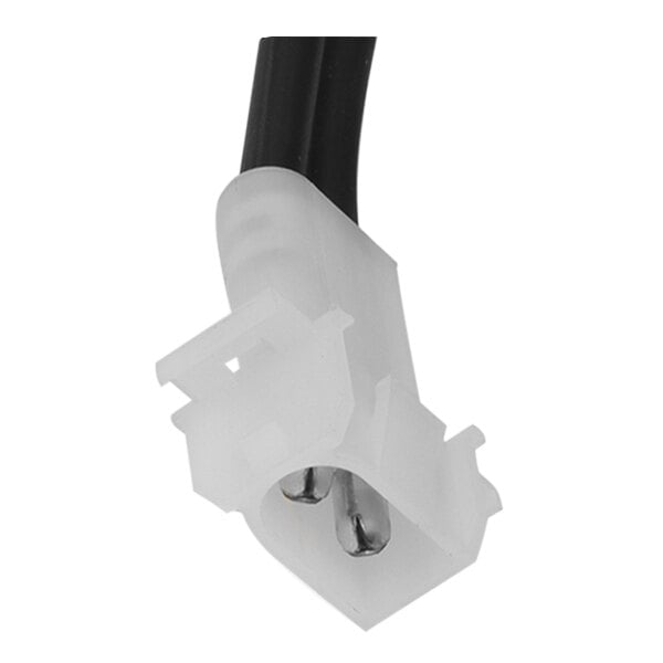 A white plastic connector with metal tips on a black object.