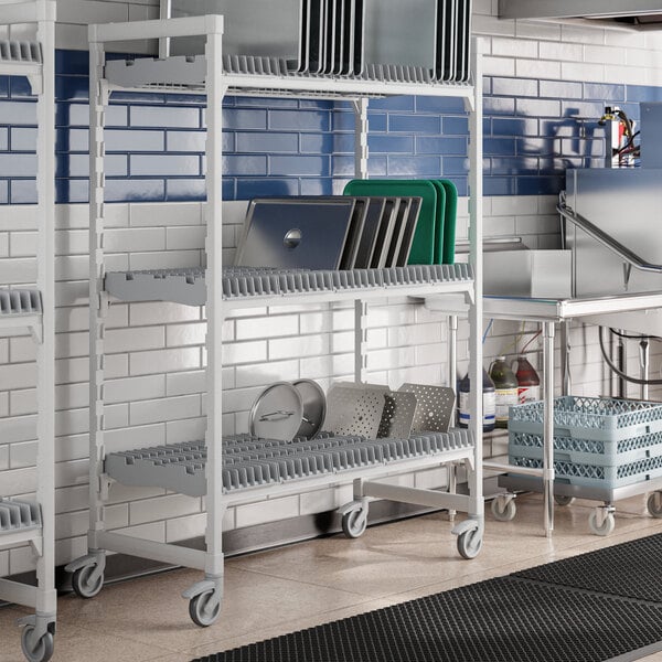 A Cambro Camshelving Premium Drying Rack Cart in a kitchen with metal shelves.