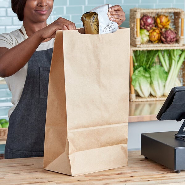 A woman holding a Duro brown paper barrel sack at a grocery store counter.