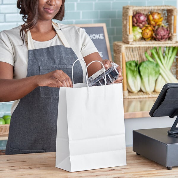 A woman in an apron holding a Duro white paper shopping bag with handles.