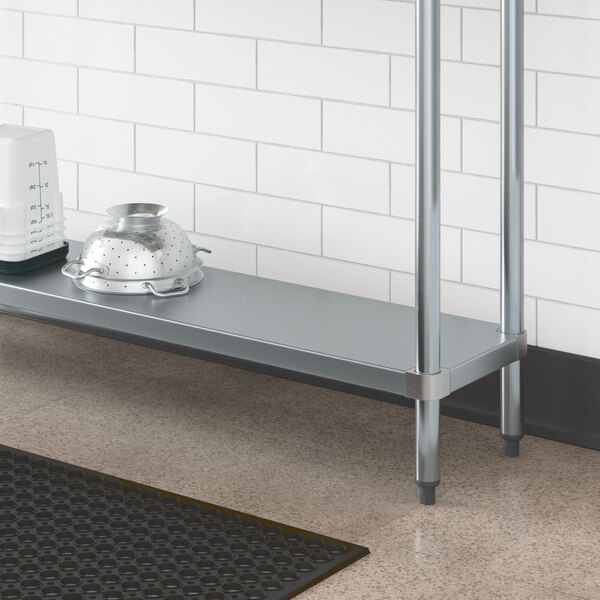 A Regency galvanized steel adjustable shelf on a metal work table with a strainer and a bowl on it.