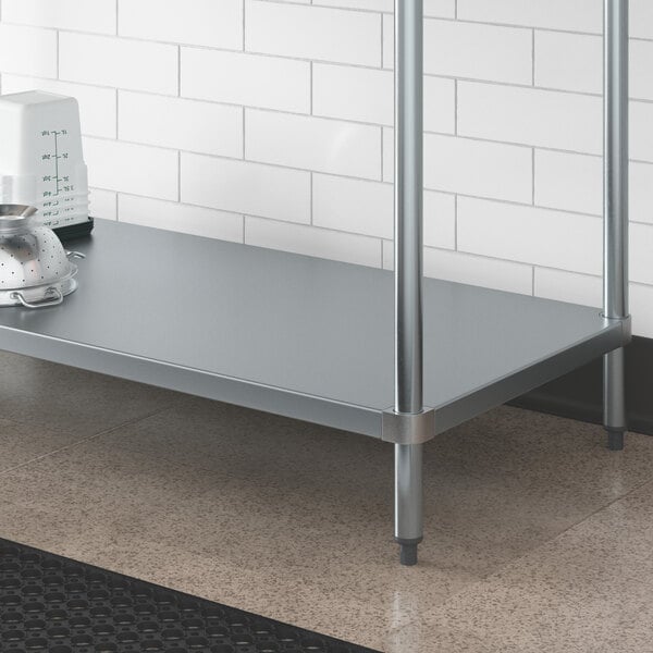 A galvanized steel Regency adjustable undershelf on a metal work table with a strainer and bowl on it.