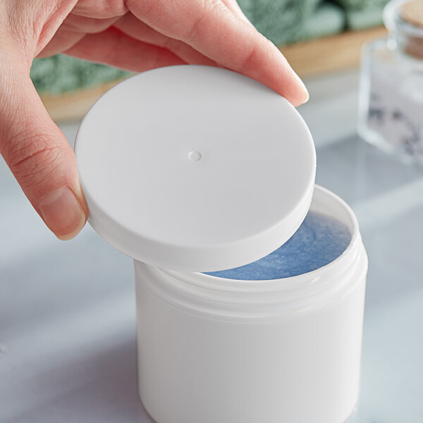 A hand holding a white container with a 70/400 Smooth White Lid.