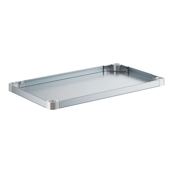 A galvanized steel rectangular shelf with metal corners on a table in a professional kitchen.