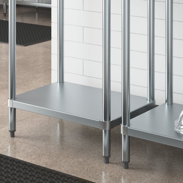 A Regency galvanized steel adjustable shelf on a metal work table with a silver object on it.